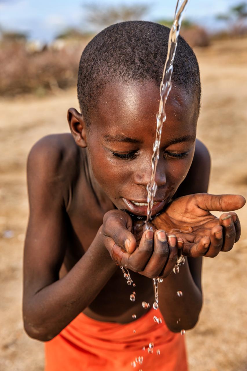 Jongen drinkt schoon water uit zijn handen